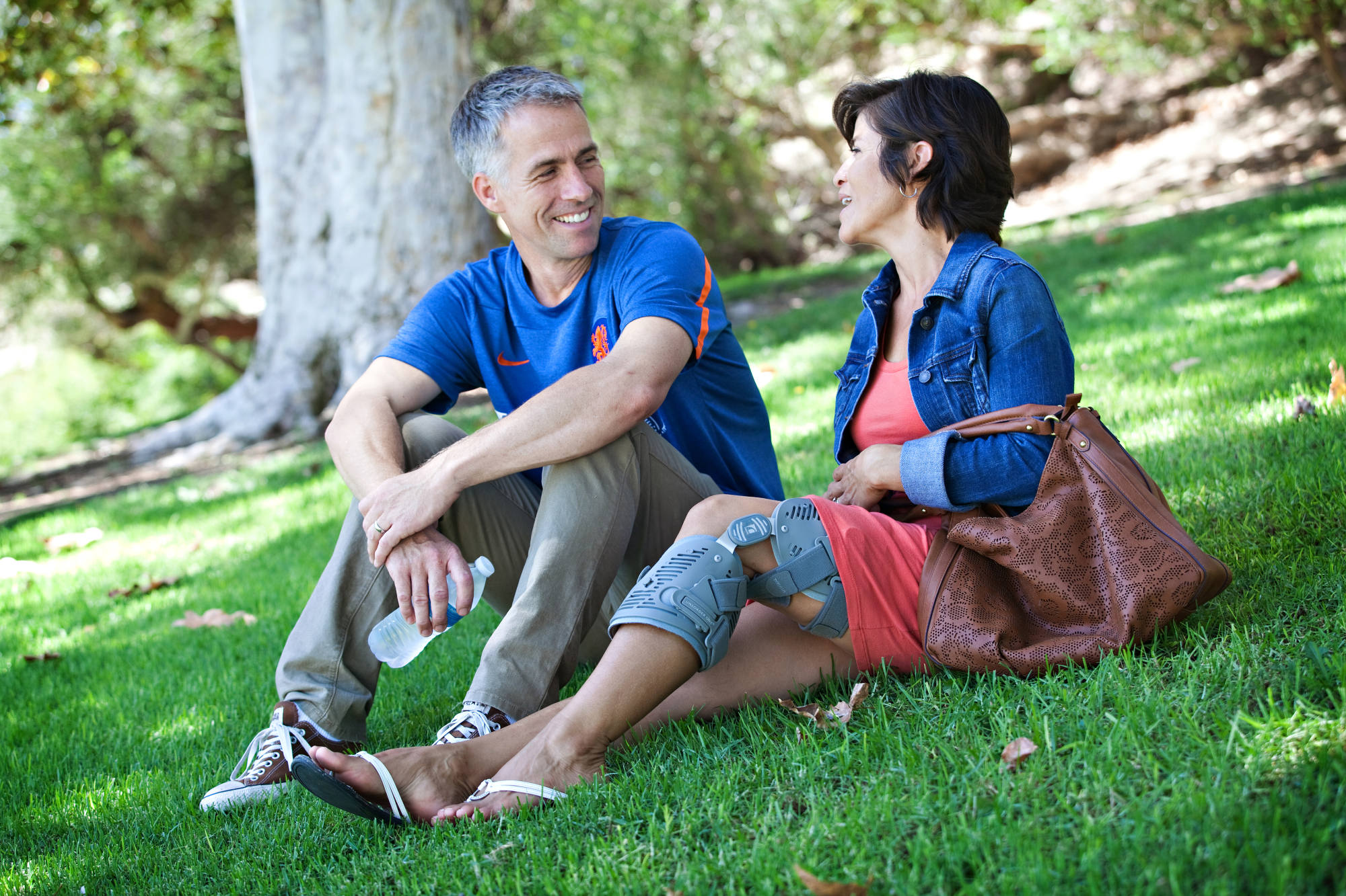 couple sitting on the grass with her in ossur unloader one knee brace